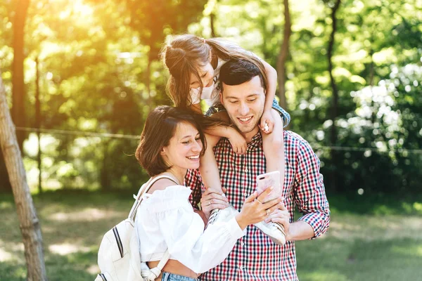 Mom dad and little daughter are looking at a smartphone — Stock Photo, Image