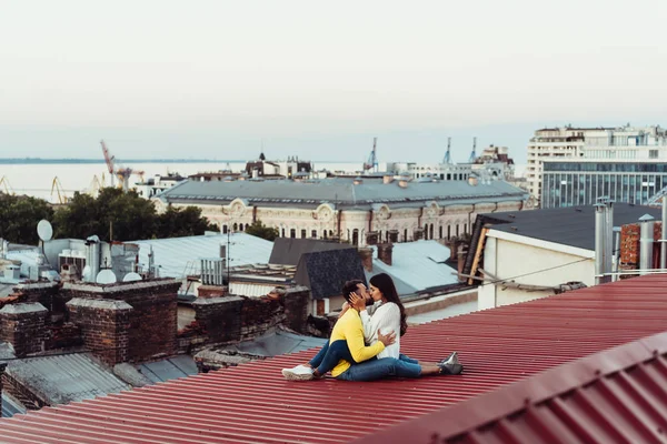 Loving young couple is sitting on the roof of the house. — Stock Photo, Image
