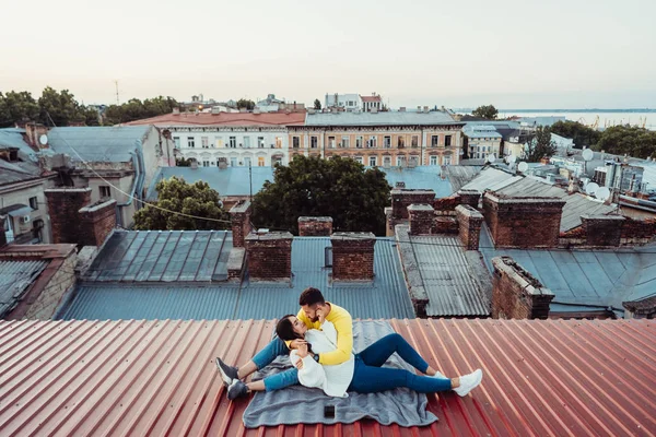 Amante jovem casal está sentado no telhado da casa. — Fotografia de Stock