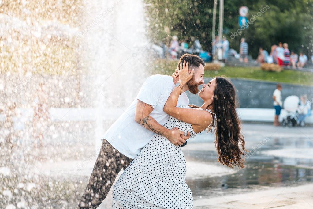 Handsome guy and beautiful girls kissing on the background of a fountain