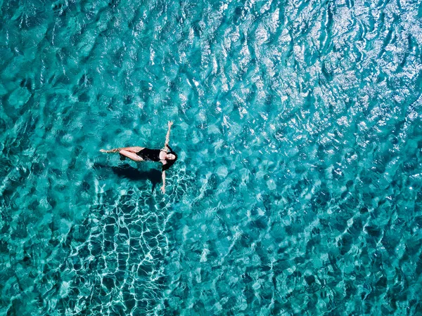 검은 수영복에 어린 소녀는 바다에서 수영. — 스톡 사진