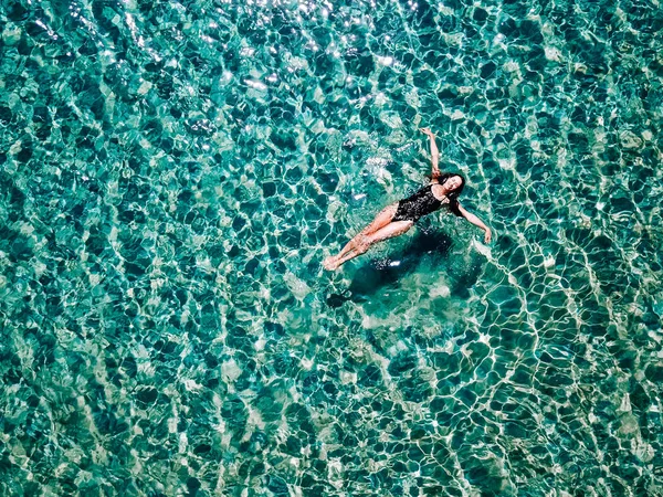 Молодая девушка в черном купальнике плавает в море . — стоковое фото