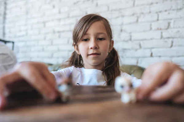 Chica jugando con pequeñas figuras sentadas en suave — Foto de Stock