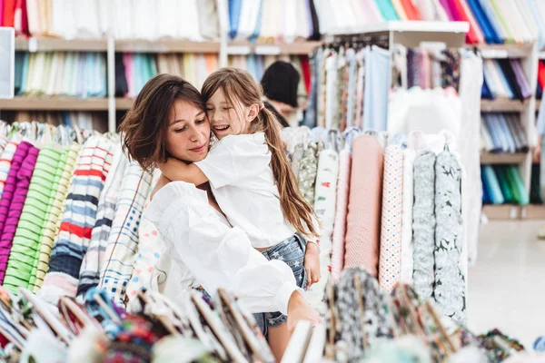 Máma a dcera v úložišti tkanina vybrat tkaniny — Stock fotografie