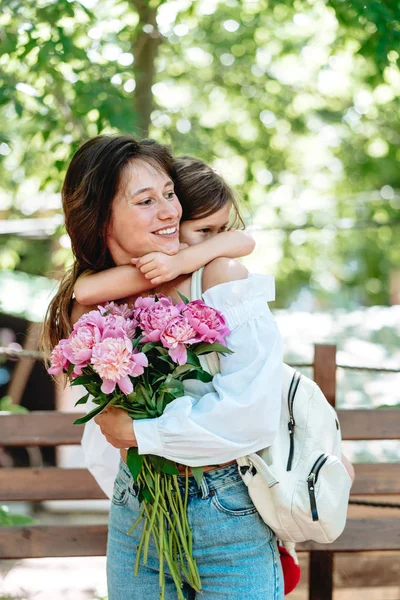 Ung mamma med en bukett blommor är att ha kul med sin dotter — Stockfoto