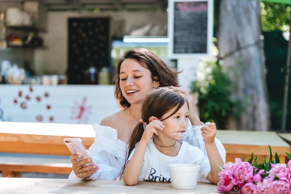 Joven madre e hija pequeña juntas en un café . — Foto de Stock