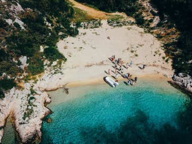 İnsanlar bir motorlu tekne yakınındaki vahşi bir plajda