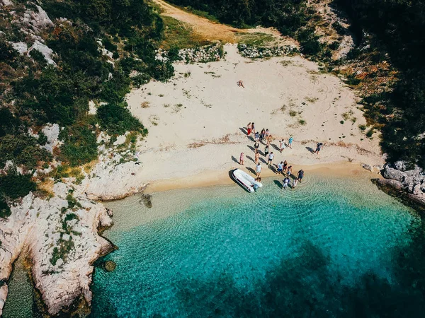 Люди на диком пляже возле моторной лодки — стоковое фото