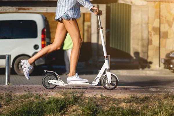 Schöne Mädchen auf einem Motorroller die Straße hinunter — Stockfoto