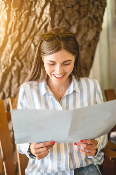 Beautiful tourist woman in restaurant watching the menu