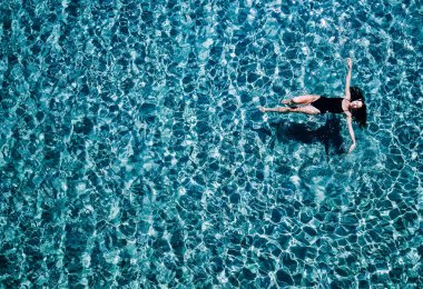 Bir siyah mayo genç kız denizde yüzüyor.