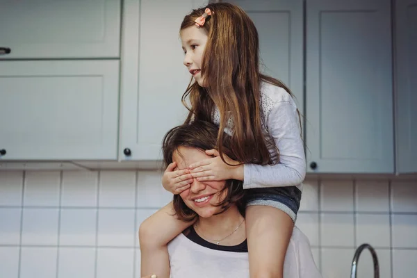 Bela pequena filha piggybacking em sua mãe feliz — Fotografia de Stock