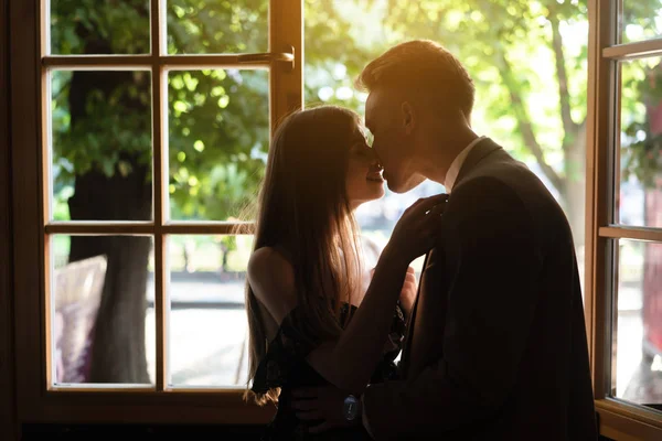 Jovem casal apaixonado de pé junto à janela — Fotografia de Stock