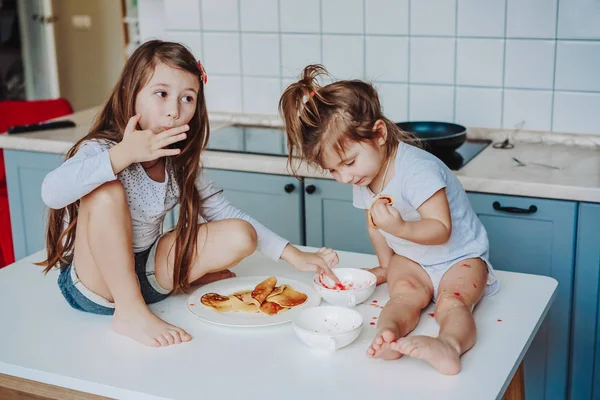 Duas meninas na cozinha sentadas na mesa. — Fotografia de Stock
