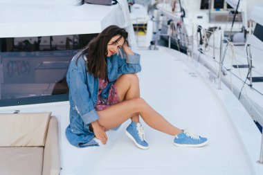 Genç güzel kız bir yatın güvertesinde oturan