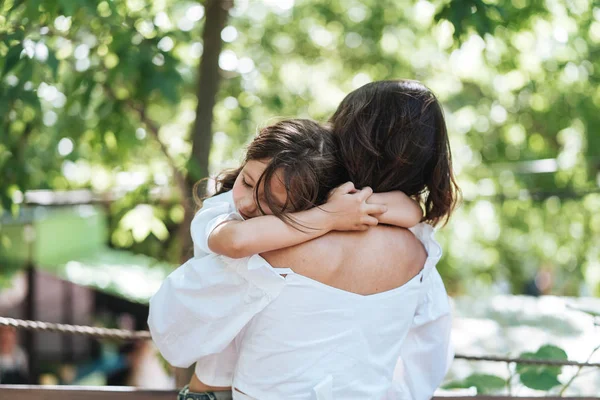 Joven madre abraza a su pequeña hija en el parque — Foto de Stock