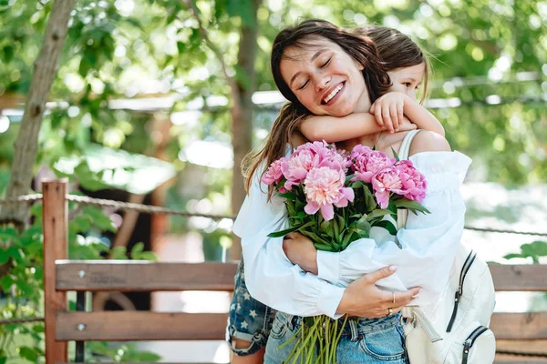 Молодая мама с букетом цветов веселится со своей дочерью — стоковое фото