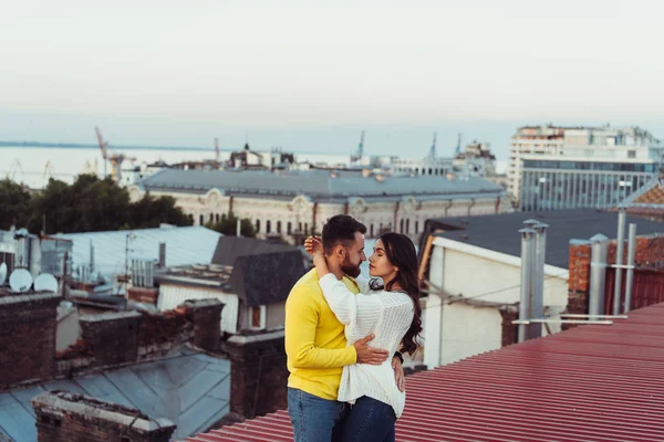 Amante jovem casal está de pé no telhado da casa. — Fotografia de Stock