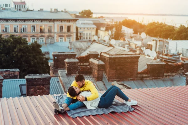 Любляча молода пара сидить на даху будинку . — стокове фото