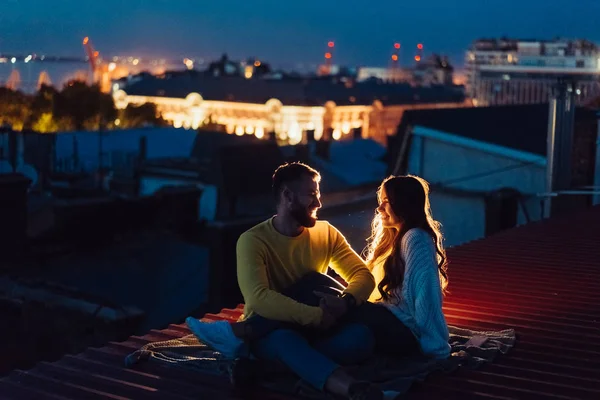 Loving couple is sitting on the roof of the house. Beautiful evening — Stock Photo, Image