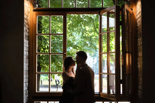 Молода пара в любові стоїть біля вікна — стокове фото