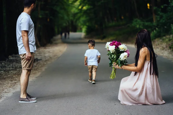 Junge Eltern gehen mit ihrem kleinen Sohn im Park spazieren. — Stockfoto