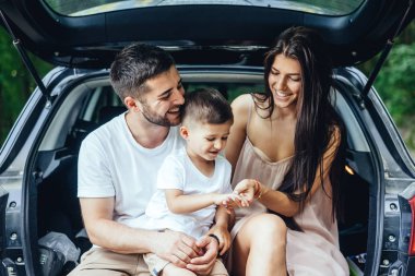Genç aile arabalarının bagajında oturmuş dinleniyor