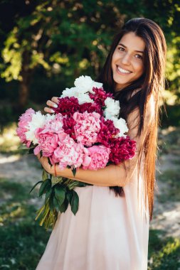 Genç, güzel bir kız yaz parkta yürüyor.