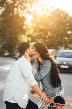 Genç, sevgi dolu ebeveynler süpermarketin yanındaki otoparkta öpüşürler..