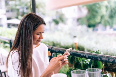 Çekici kadın bir telefon ile bir yaz sokak kafede oturuyor.