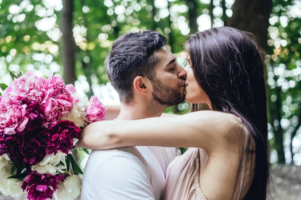 Jovem casal está se beijando na estrada em um parque de verão . — Fotografia de Stock