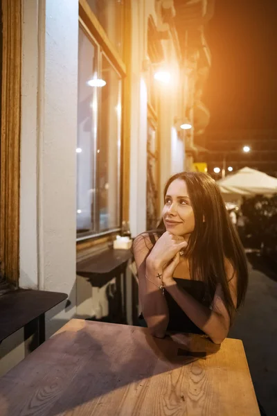 Красивая девушка, сидящая одна в кафе ночью  . — стоковое фото