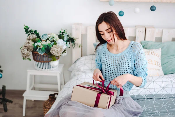 ผู้หญิงนั่งบนเตียงพร้อมกล่องของขวัญ — ภาพถ่ายสต็อก