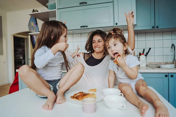 Mom and two daughters eat pancakes — Stock Photo, Image