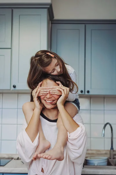 Bela pequena filha piggybacking em sua mãe feliz — Fotografia de Stock