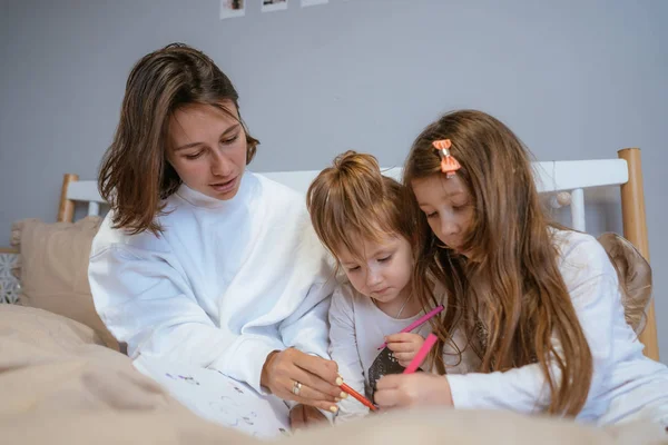 Anne ve iki kızı yatakta çizmek — Stok fotoğraf