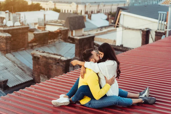 Amante jovem casal está sentado no telhado da casa. — Fotografia de Stock