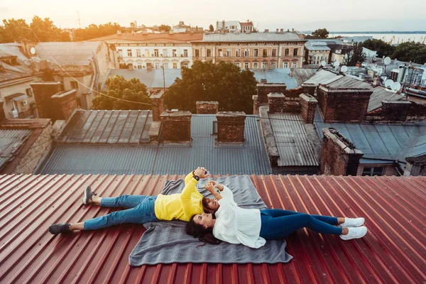 Красивий хлопець і молода дівчина лежать на даху і тримають шарфони . — стокове фото