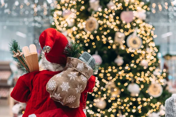 Papai Noel por trás com saco de presente no fundo da árvore de Natal bokeh . — Fotografia de Stock