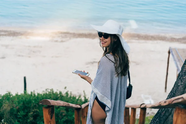 Aantrekkelijke vrouw komt neer op de zee met een telefoon. — Stockfoto