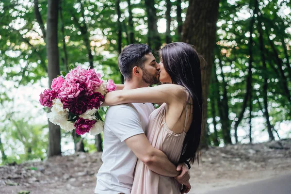 Young couple is kissing on the road in a summer park. — Stock Photo, Image