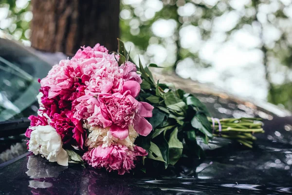 Beautiful bouquet of peonies lies on the hood of the car. — Stock Photo, Image
