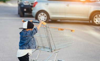 Küçük bir çocuk ve park yerinde büyük bir araba