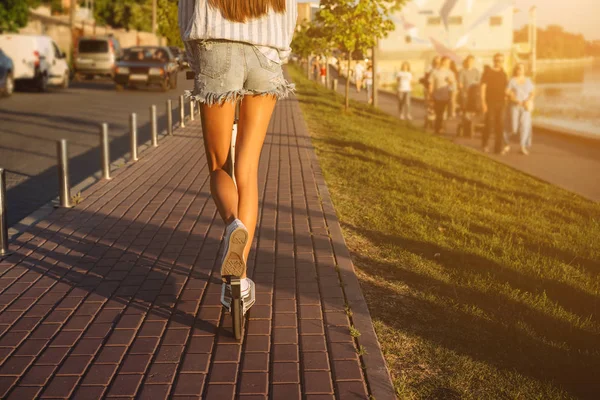 Beautiful girl riding a scooter down the street — Stock Photo, Image