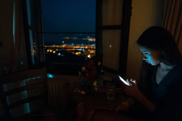 Γυναίκα χρησιμοποιώντας έξυπνο τηλέφωνο για σε απευθείας σύνδεση στο σπίτι το βράδυ — Φωτογραφία Αρχείου