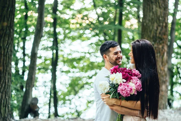 Jovem, casal feliz está andando ao longo da estrada em um parque de verão . — Fotografia de Stock