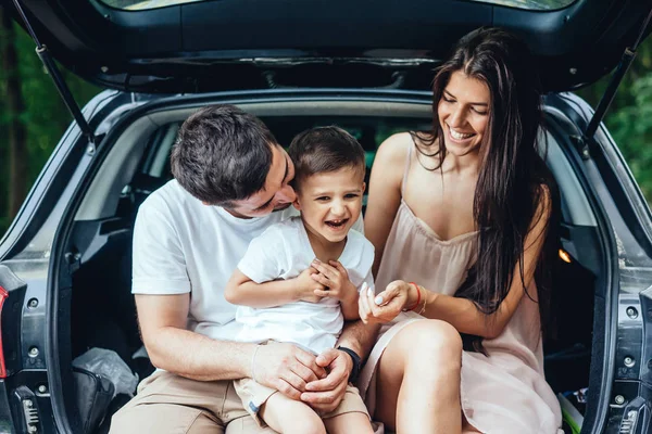 La giovane famiglia sta riposando nel bagagliaio della loro auto — Foto Stock