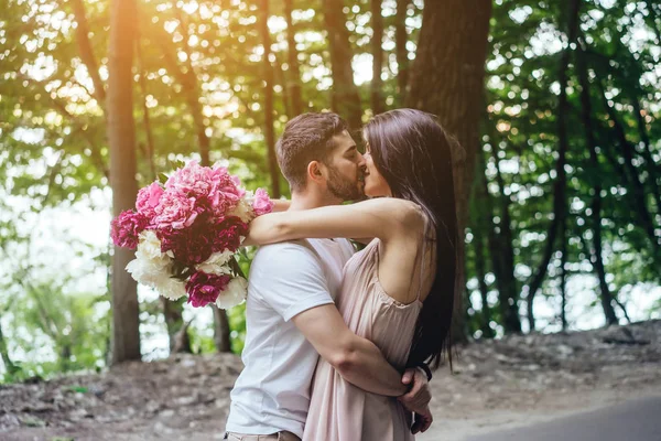 Jovem casal está se beijando na estrada em um parque de verão . — Fotografia de Stock
