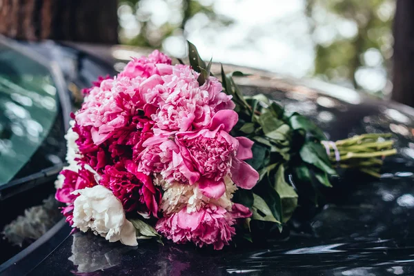 Beautiful bouquet of peonies lies on the hood of the car. — Stock Photo, Image