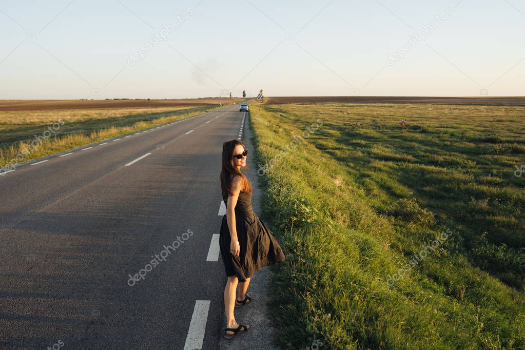 A young girl is walking along the road. She looks around.